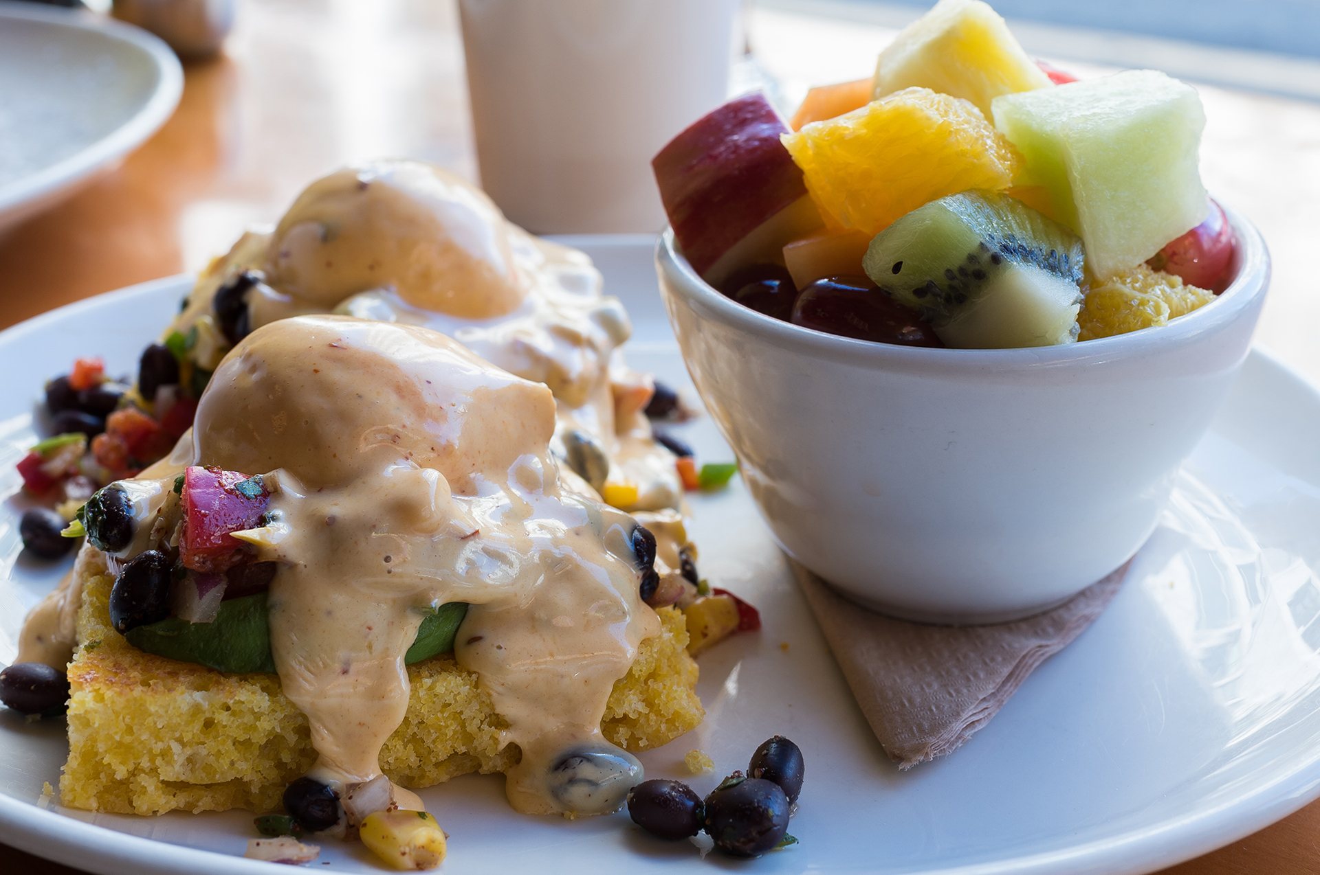 San Diego eggs Benedict on cornbread with fresh fruit